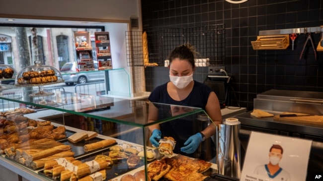 na mujer con mascarilla prepara sandwiches en Barcelona el sábado 14 de marzo de 2020. El jefe de gobierno español anunció el sábado un estado de emergencia de dos semanas en un intento por contener el brote de un nuevo coronavirus.