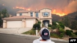 Un homme regarde le feu ravager une colline près du lac Elsinore, en Californie, au sud-est de Los Angeles, le 9 août 2018.
