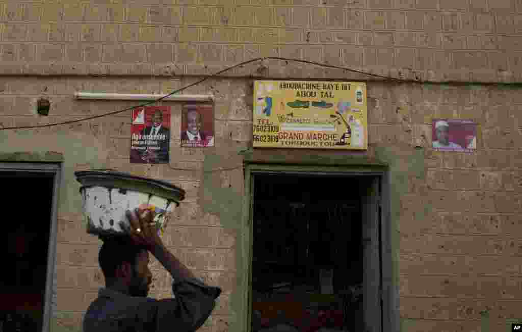 A vendor walks past a shop decorated with election posters supporting presidential candidate Dramane Dembele, in the central market area of Timbuktu, Mali, July 22, 2013.