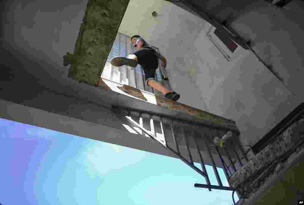Un joven se sube a la casa dañada de su tía, donde las escaleras hacia la sala de estar se derrumbaron después de que un terremoto golpeara Guánica, Puerto Rico, el lunes 6 de enero de 2020.