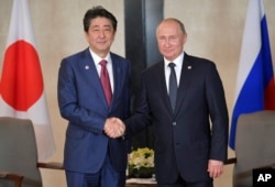 Russian President Vladimir Putin, right, and Japanese Prime Minister Shinzo Abe pose for a photo during the ASEAN-Russia Summit in the ongoing 33rd ASEAN Summit and Related Summits Wednesday, Nov. 14, 2018 in Singapore. (Alexei Druzhinin, Sputnik, Kremlin Pool Photo via AP)