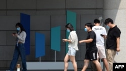 北京字节跳动总部大楼旁几个青年边走路边看手机。（2020年7月6日）