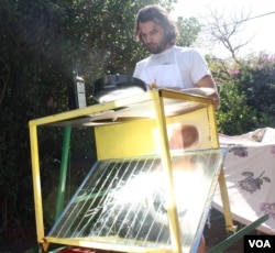 SunFire solar power technologist Zander van Manen cooks on the Sol-4, with sunlight reflected onto a pan. (Darren Taylor for VOA)