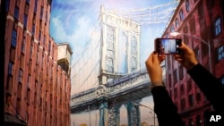 A woman takes a picture of a painting by Bob Dylan called "Manhattan Bridge, Downtown New York" on display at the exhibition called Bob Dylan The Beaten Path, at the Halcyon Gallery in London, Nov. 1, 2016. The exhibition opens on Nov. 5 and runs until Dec. 11, 2016.