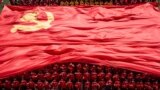 FILE - University students display the flag of the Communist Party of China to mark the party's 100th anniversary during an opening ceremony of the new semester in Wuhan in China's central Hubei, September 10, 2021.