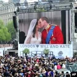 Royal supporters watch Britain's Prince William kissing his wife Kate, Duchess of Cambridge on a giant screen in Trafalgar Square in central London, after the wedding ceremony, on April 29, 2011.