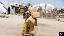 FILE - A girl carries empty plastic containers at a camp Maiduguri, Nigeria, Aug. 28, 2016.