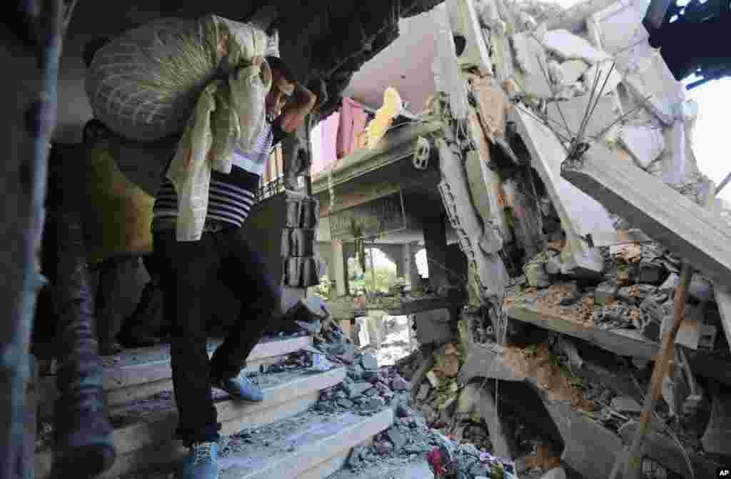 Palestinians carry belongings in a house after it was hit by an Israeli missile strike in Gaza City, July 11, 2014. 