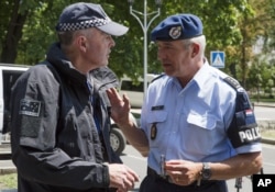 Dutch, right, and Australian policemen talk in the city of Donetsk, eastern Ukraine, July 27, 2014.