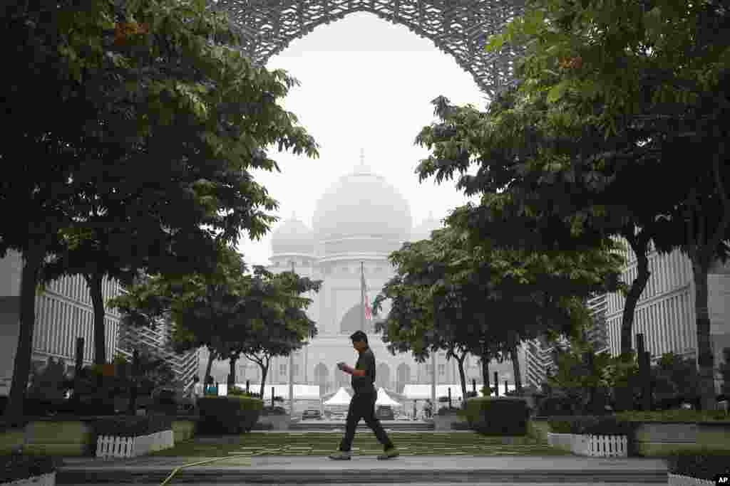 Một người đàn ông Malaysia đi ngang qua Điện Công lý bị bao phủ trong khó mù ở thành phố Putrajaya, Malaysia. Cháy rừng do phá rừng bất hợp pháp ở đảo Sumatra và Borneo của Indonesia thường gây ra khói mù gây nghẹt thở cho những nước láng giềng như Malaysia và Singapore.