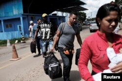 FILE - Venezuelans walk to show their passports or identity cards at the Pacaraima border control, Roraima state, Brazil, Nov. 16, 2017.