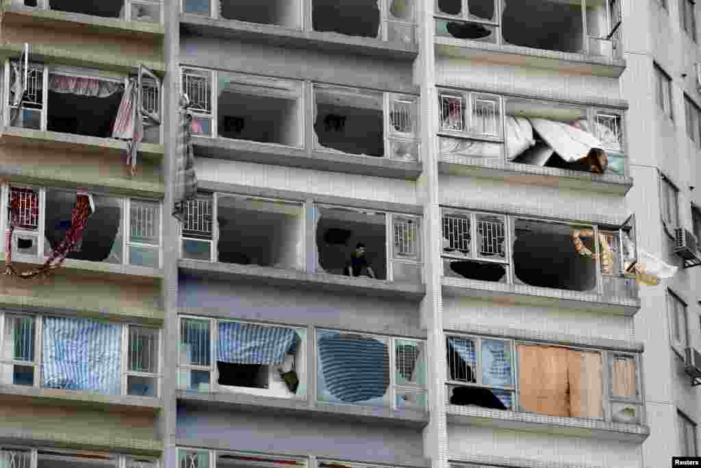 A man looks out from inside an apartment where some windows have been broken by typhoon Hato in Macau, China.