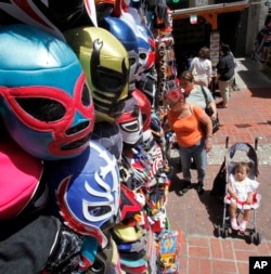 Masks hang over shoppers on Olvera Street during Cinco De Mayo festivities