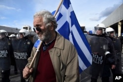 An opponent of Prespa Agreement holds a Greek flag in front of riot police during a protest in Evzones at the Greek-Macedonian border, Jan. 24, 2019.
