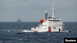A Chinese Coast Guard vessel, with the disputed oil rig in the background, is seen in the South China Sea June 13, 2014.