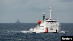 FILE - A Chinese Coast Guard vessel, with the disputed oil rig in the background, is seen in the South China Sea June 13, 2014.