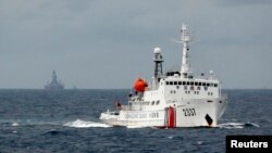 Tàu cảnh sát biển Trung Quốc phía trước giàn khoan dầu Hải Dương ở Biển Ðông, ngày 13/6/2014. Bộ Ngoại giao Trung Quốc xác nhận giàn khoan Hải Dương 981 ngày 15/7 đã hoàn tất công tác thăm dò ngoài khơi quần đảo Hoàng Sa ‘đúng kế hoạch.’