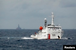 FILE - A Chinese Coast Guard vessel, with the disputed oil rig in the background, is seen in the South China Sea, June 13, 2014.