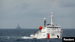 南中国海上的一艘中国海警船，不远处是中国的海上钻井平台。（2014年6月） 