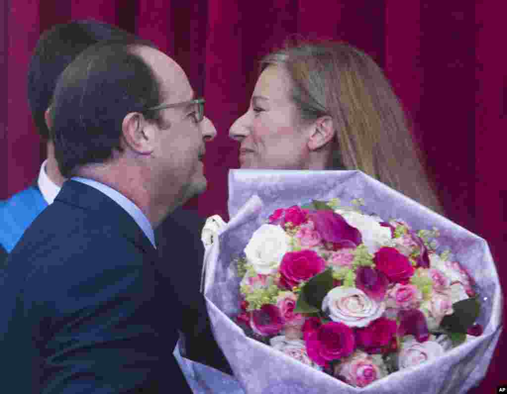 French violonist Anne Gravoin, the wife of French PM Manuel Valls, receives flowers from President Francois Hollande after Valls was awarded the Grand Cross of National Merit at the Elysee Palace in Paris, Oct. 22, 2014. 