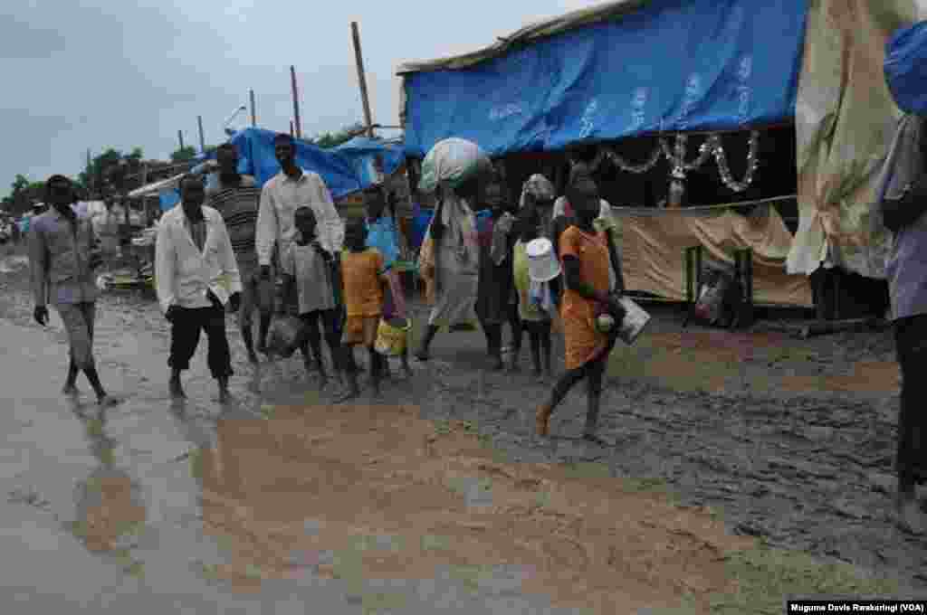 People walk along dirt roads that have been turned into streams of mud by the rains, in the UNMISS base in Malakal, South Sudan, where 19,000 people have sought shelter from months of fighting.