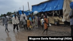 People walk along dirt roads that have been turned into streams of mud by the rains, in the UNMISS base in Malakal, South Sudan, where 19,000 people have sought shelter from months of fighting.