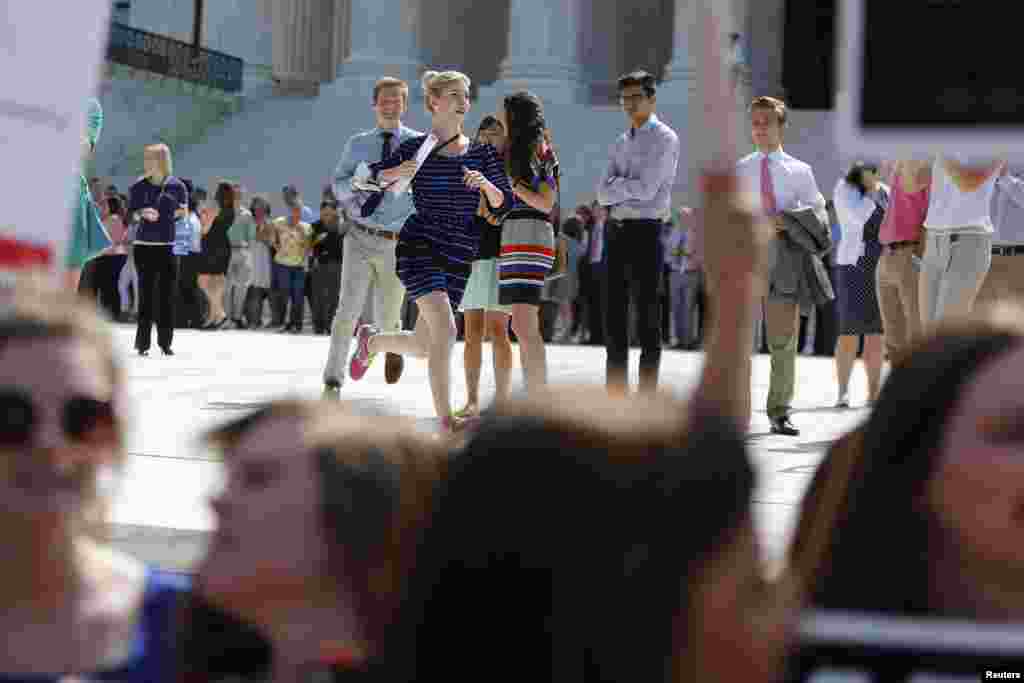 Reporters run from the courthouse with paper copies of the U.S. Supreme Court decision for the Hobby Lobby ruling, in Washington, June 30, 2014.