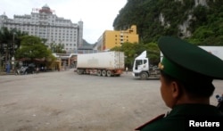 FILE - A guard monitors people and container trucks crossing the Tan Thanh border gate with China in Vietnam's northern Lang Son province, July 30, 2014.