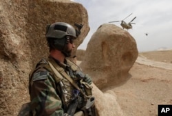 FILE - A U.S. special forces soldier takes cover as two Chinook Ch-47 helicopters come in for a landing with supplies in Afghanistan, Sept. 16, 2009.