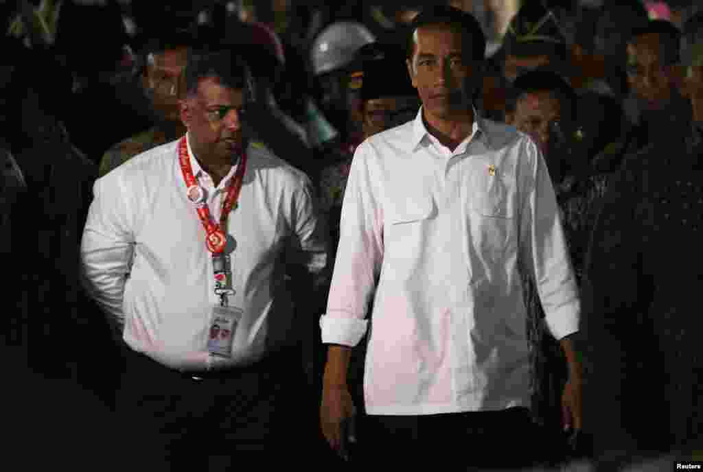 Indonesia's President Joko Widodo, right, walks beside AirAsia's CEO Tony Fernandes after meeting with family members of passengers onboard AirAsia flight QZ8501 in Juanda International Airport, Surabaya, Dec. 30, 2014.