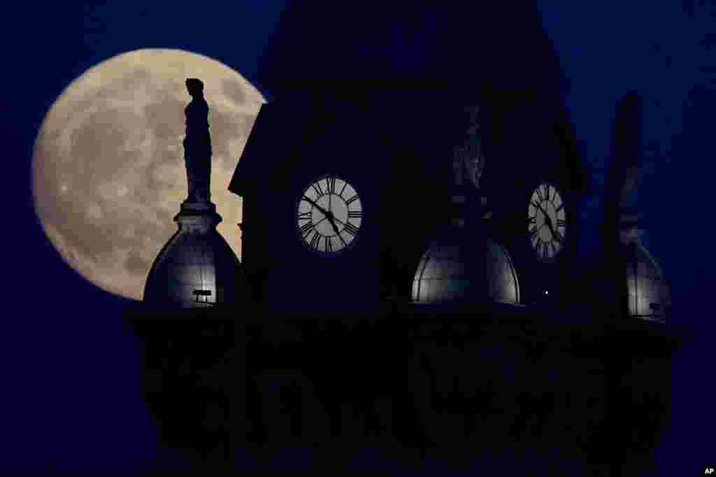 The moon rises in its waxing gibbous stage behind a statue atop the Erie County Court Building, in Buffalo, New York, Dec. 2, 2017.