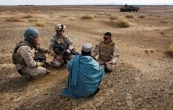 Sersan Marinir Amerika Serikat. Isaac Tate (kiri) dan Kpl. Aleksander Aleksandrov (tengah), mewawancarai seorang pria Afghanistan setempat dengan bantuan seorang penerjemah dari MEB, 11 Desember 2009. (AP)