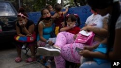 Sejumlah perempuan beserta anak-anak mereka tampak menunggu giliran untuk mendapatkan vaksin di sebuah taman kanak-kanak di Caracas, Venezuela, pada 9 Desember 2021. (Foto: AP/Ariana Cubillos)