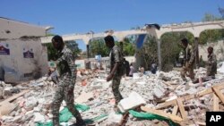 Somali soldiers walk near a destroyed building after a car bomb in Mogadishu, May 14, 2019.