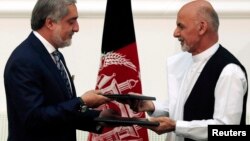 FILE - Afghan rival presidential candidates Abdullah Abdullah (L) and Ashraf Ghani exchange signed agreements for the country's unity government in Kabul, Sept. 21, 2014.
