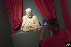 A woman photographs the sculpture of Soviet founder Vladimir Lenin during the opening of "Energy of the Dream. Сentennial of the 1917 Revolution" exhibition in Moscow, Nov. 2, 2017.