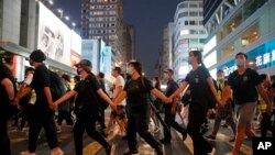 Masked protesters hold hands to form a human chain to protest against the ban on masks in Hong Kong, Saturday, Oct. 5, 2019. 