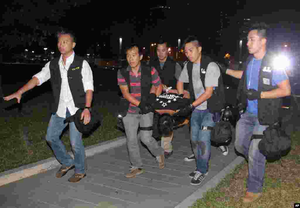 Ken Tsang, center, a member of a local pro-democracy political party, is carried by plainclothes police officers after a clash between protesters and police in an occupied area near the government headquarters in Hong Kong Wednesday, Oct. 15, 2014. Hundre