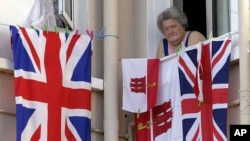 FILE - A woman resident of Gibraltar looks out of a window behind flags of England and Gibraltar, Aug. 4, 2004. For British-ruled Gibraltarians, London's membership in the EU prodives a safety net they would lose if Britain were to exit the EU.