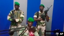 Seorang prajurit yang mengidentifikasi dirinya sebagai Letnan Obiang Ondo Kelly, komandan Pengawal Republik, membaca pernyataan di siaran televisi negara dari Libreville, Gabon, mengatakan militer telah mengambil alih kendali pemerintah (7/1). (Gabon State TV via AP)
