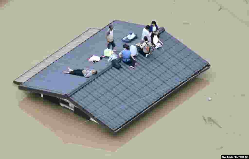 An aerial view shows local residents seen on the roof of submerged house in a flooded area as they wait for a rescue in Kurashiki, southern Japan, in this photo taken by Kyodo July 7, 2018.