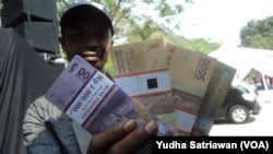 Seorang warga menunjukkan uang tunai lembaran baru hasil penukaran di mobil perbankan Solo, Solo, 5 Juni 2018. (Foto: Yudha Satriawan)