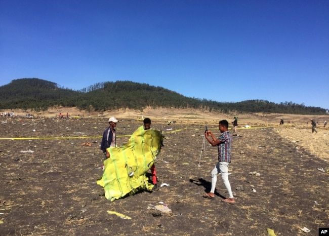 A civilian takes a photograph of the wreckage at the scene of the Ethiopian Airlines Flight 302 plane crash, March 10, 2019.