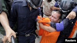 Cambodian police detain a Buddhist monk who was demonstrating for the release of seven convicted land-rights activists in Phnom Penh, Nov. 11, 2014.