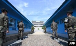 FILE - South Korean soldiers (front) and North Korean soldiers (rear) stand guard before the military demarcation line on the each side of the truce village of Panmunjom in the Demilitarized zone (DMZ) dividing the two Koreas.