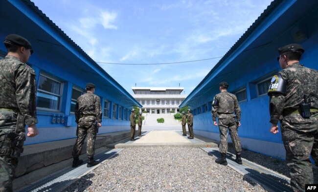 FILE - South Korean soldiers (front) and North Korean soldiers (rear) stand guard before the military demarcation line on the each side of the truce village of Panmunjom in the Demilitarized zone (DMZ) dividing the two Koreas.