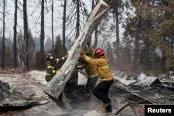 Firefighters move debris while recovering human remains from a trailer home destroyed by the Camp Fire in Paradise, California, U.S., Nov. 17, 2018.