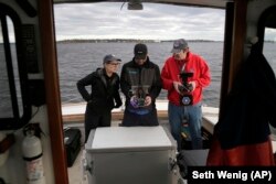 Artist Melinda Hunt, president of The Hart Island Project, left, and drone operator Parker Gyokeres, right, look over the video recorded by Daniel Herbert from the drone flight over Hart Island in New York.