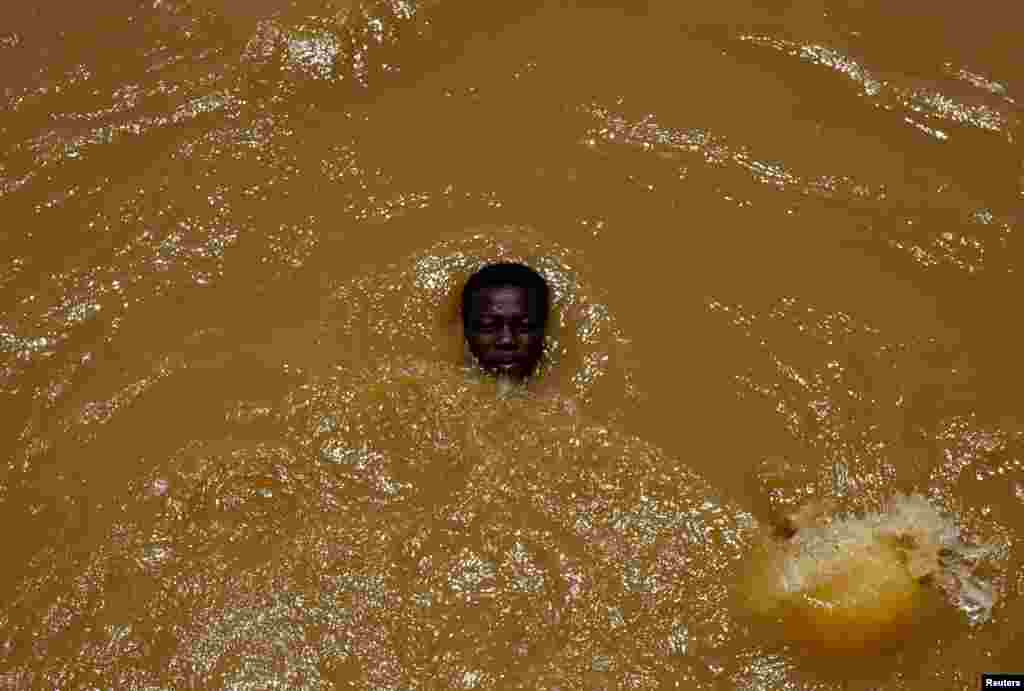 A young man cools himself off in an irrigation channel near Khartoum, Sudan.