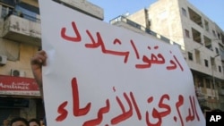 Syrians protest in the city of Banias holding up a sign that reads in Arabic, "Stop the innocent blood bath" on April 26, 2011